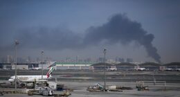 Smoke rises from Dubai International Airport on Sunday morning as Emirates planes remain grounded
