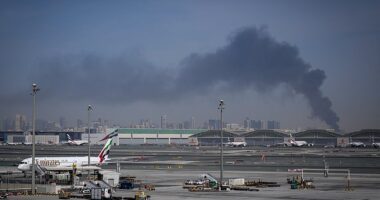Smoke rises from Dubai International Airport on Sunday morning as Emirates planes remain grounded