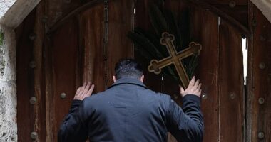 Issa Kassissieh (pictured), a Palestinian Christian who is popular for being the Santa Claus of the city, stands holding a cross and a palm frond at the doors of the Church of the Holy Sepulchre after finding them locked, following the cancellation of the traditional Palm Sunday procession from the Mount of Olives