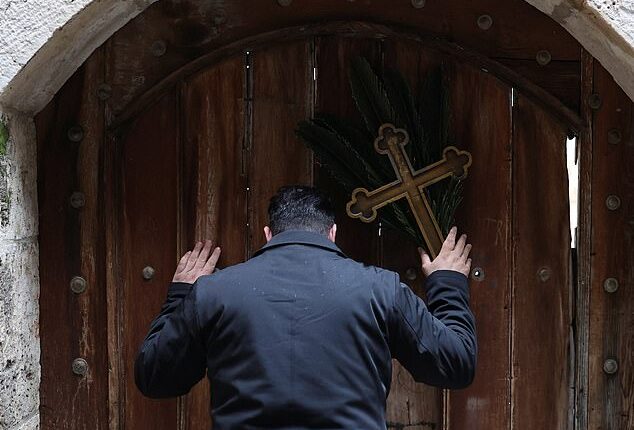 Issa Kassissieh (pictured), a Palestinian Christian who is popular for being the Santa Claus of the city, stands holding a cross and a palm frond at the doors of the Church of the Holy Sepulchre after finding them locked, following the cancellation of the traditional Palm Sunday procession from the Mount of Olives