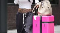 Katie Price flashed her tattooed torso on return from Dubai on Friday as husband Lee Andrews is accused of 'failing to pay a woman back $1000' after she invested in his dissolved business - claims he denies