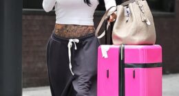 Katie Price flashed her tattooed torso on return from Dubai on Friday as husband Lee Andrews is accused of 'failing to pay a woman back $1000' after she invested in his dissolved business - claims he denies