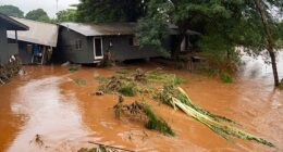 A view of a storm-damaged home near floating felled branches in flood waters caused by severe rains in Waialua