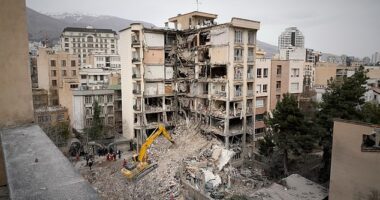 Iranian Red Crescent emergency workers use a bulldozer to clear rubble from a residential building that was hit in an earlier US-Israeli strike in Tehran on Monday