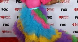 Singer Cheryl Porter, 53, made a very bold entrance in a rainbow-colored gown that boasted bright pink puff-ball shoulders and a tiered tulle skirt that flowed down into a dramatic train