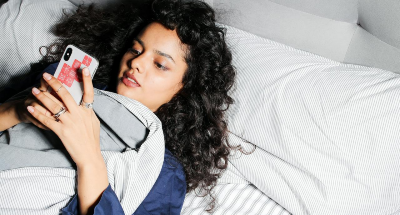 woman scrolling on phone in bed