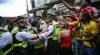 Rowdy Arsenal fans in confrontation with police officers, as one supporter puts his middle fingers up to them