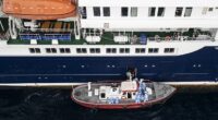 Aerial view shows health personnel assisting patients onto a boat from the cruise ship MV Hondius, while stationary off the port of Praia