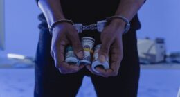 Person in handcuffs holding rolls of money.