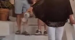 Footage shared to social media showed the woman carrying a clear plastic container filled with what appears to be ash through the picturesque streets of Oia