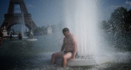 A person cools off at Trocadero fountain near the Eiffel Tower during a heat wave in Paris, Wednesday