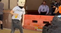 Among those rallying outside of Turning Point USA's Women's Summit in Texas, one protester was seen in a head covering made to resemble Kirk, who was assassinated last year
