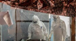 Healthcare workers tend to an Ebola patient at the Rwampara Treatment Center in Ituri, Congo