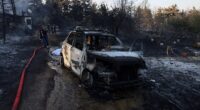 Firefighters try to extinguish a wildfire close to a burnt house and a car near the village of Liti, Thessaloniki, Greece