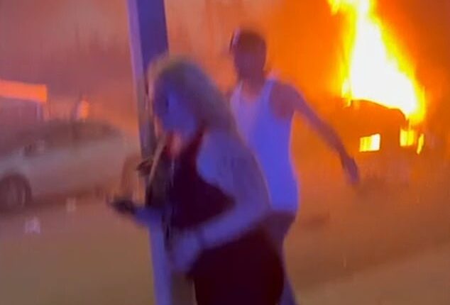 Bystanders are seen running away after a vehicle caught fire after fireworks exploded in Chino, California on Saturday night